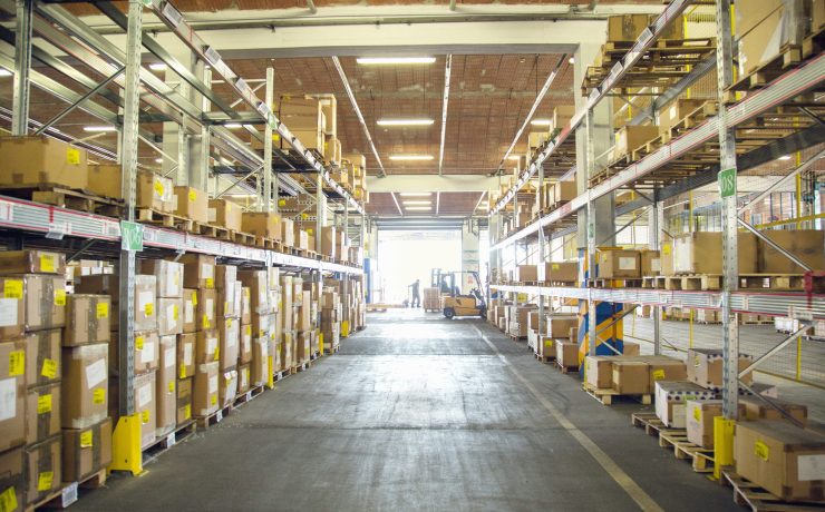 Forklift trucks and drivers working in distribution warehouse aisle