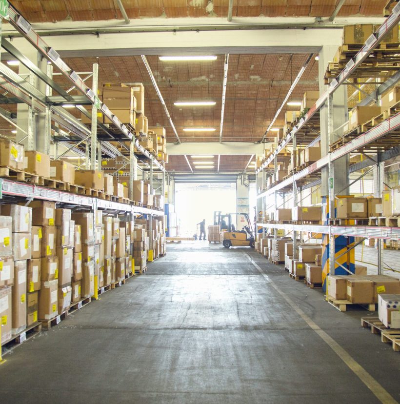 Forklift trucks and drivers working in distribution warehouse aisle